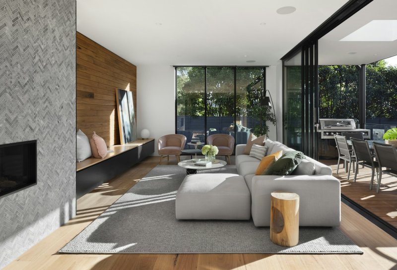 Living room with a stone and walnut feature wall, a deep corner sofa and sliding doors to a terrace